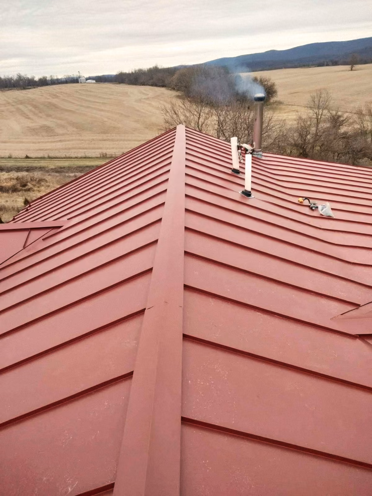 New red standing-seam metal roof installed by Modern Renovations overlooking the valley